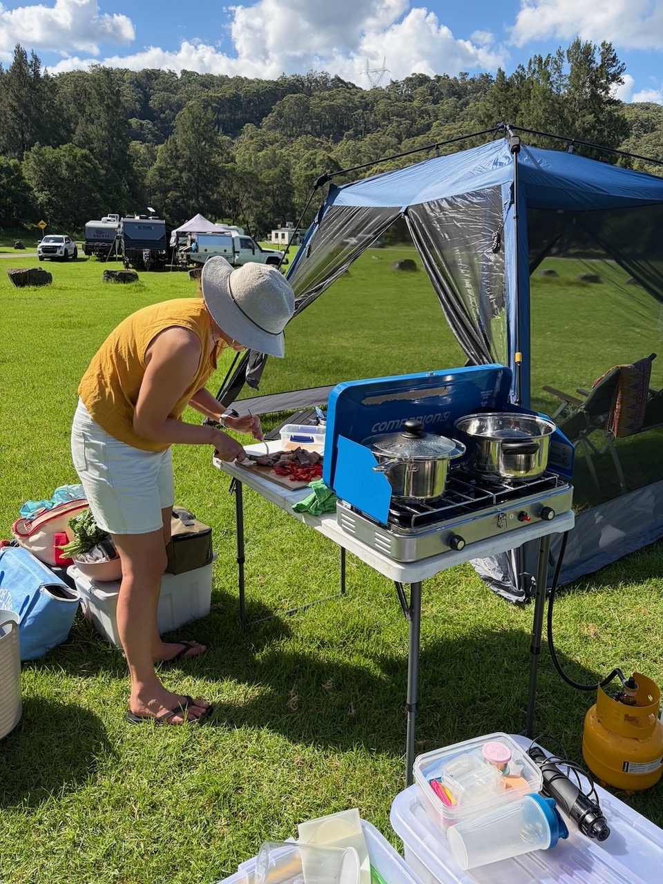 Steph preparing food beside the camp stove at Bendeela on a sunny afternoon.