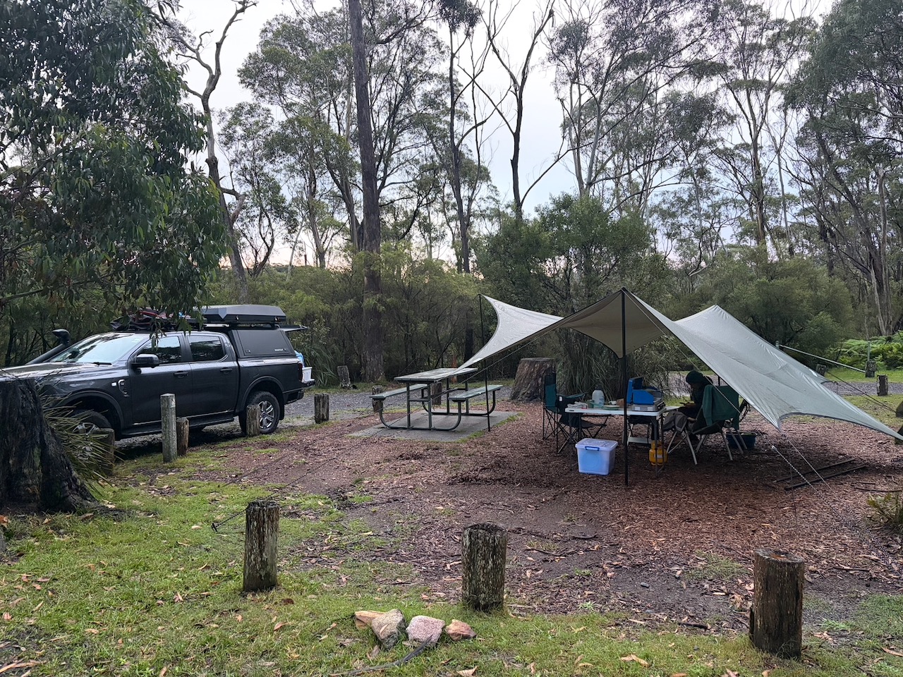 Roger the Ranger parked beside the tarp setup at Carrington Falls campground in wet conditions.