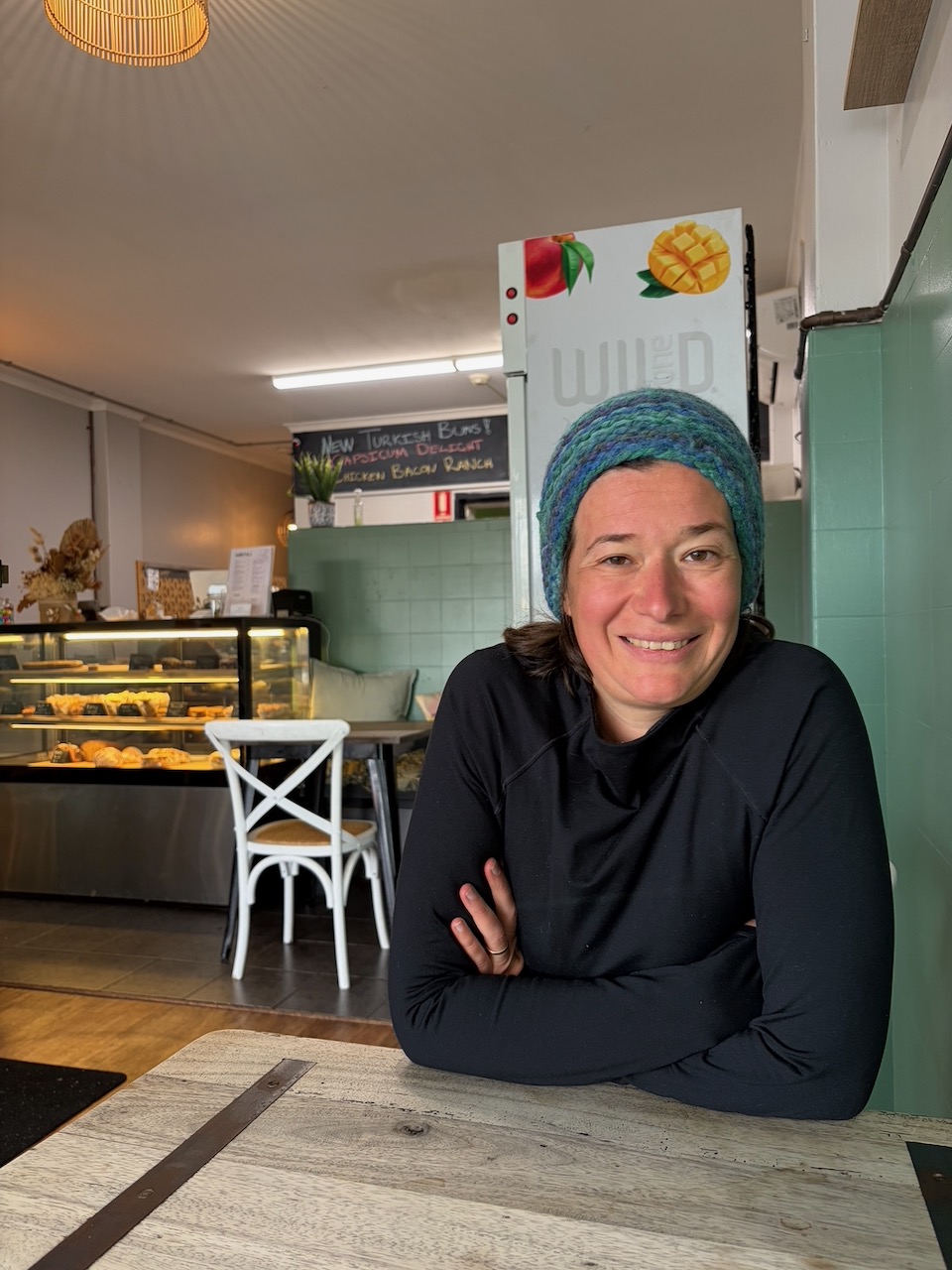 Steph smiling at a cafe table in Wollongong on a cold wet morning.