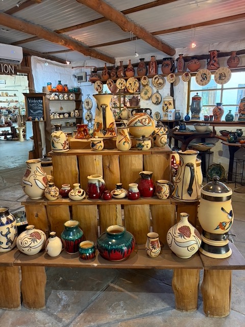 The interior of Pilliga Pottery shop, with handmade vases, bowls and decorative pieces arranged on timber shelving throughout a whitewashed room.