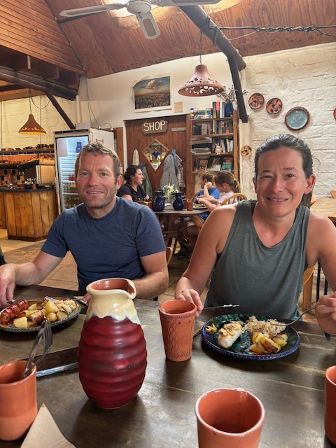 Matt and Steph sitting at a table inside the Pilliga Pottery cafe with their lunch, surrounded by pottery and warm timber interiors.