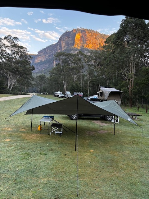 Two tarps set up side by side at Coorongooba with sandstone cliffs glowing orange behind in the morning light.